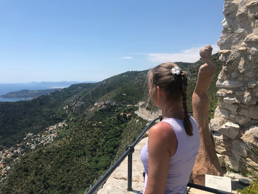 Blick auf Mittelmeer und Cap d‘Antibes vom Jardin Exotique in Eze, im Vordergrund Skulptur Melisande von Jean-Philippe Richard und Frau, die auf das Meer schaut